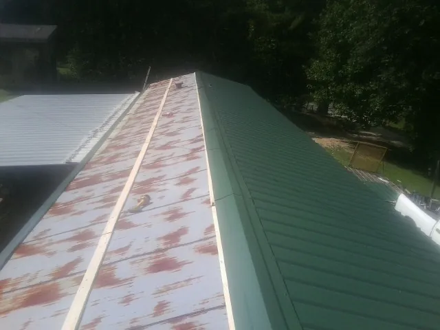Old rusted panels beside newly installed green metal roofing — Wind Damage Roof Repair by Roofing Brothers in Oshkosh