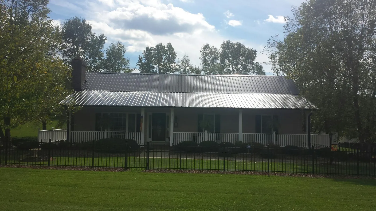Gray metal roof on a brick ranch with a full width front porch — Gutter Guard Installation work by our crew in Oshkosh